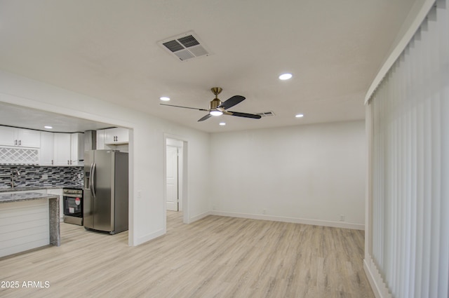 kitchen featuring stainless steel appliances, white cabinetry, tasteful backsplash, and light wood-type flooring