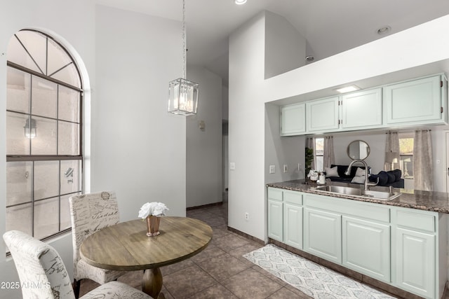 kitchen featuring hanging light fixtures, tile patterned floors, sink, vaulted ceiling, and a chandelier