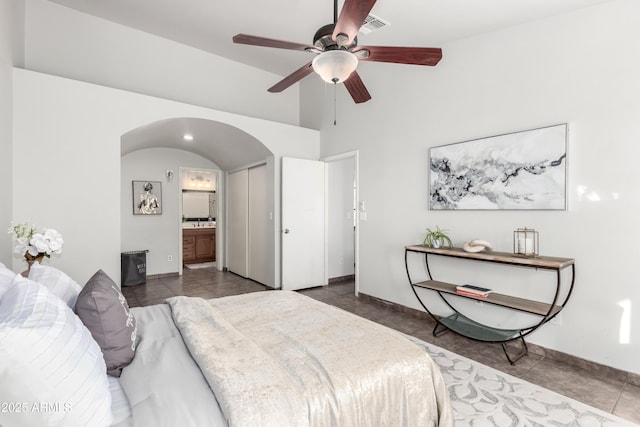 bedroom featuring a closet, ensuite bathroom, dark tile patterned flooring, and ceiling fan