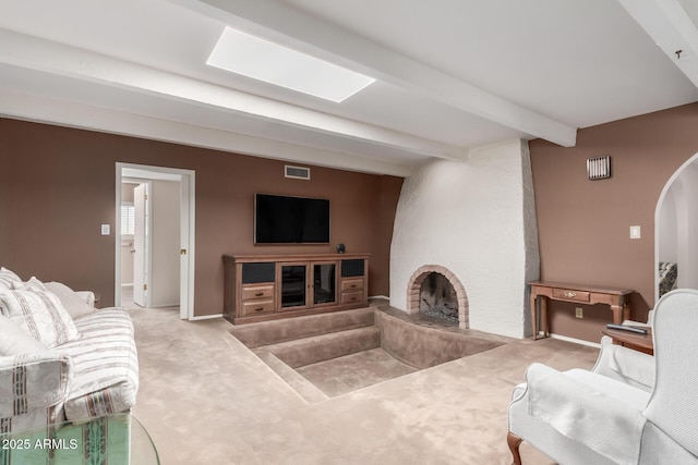 carpeted living room with a fireplace, beam ceiling, arched walkways, and baseboards