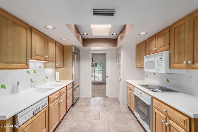 kitchen featuring white appliances, baseboards, light countertops, a raised ceiling, and backsplash