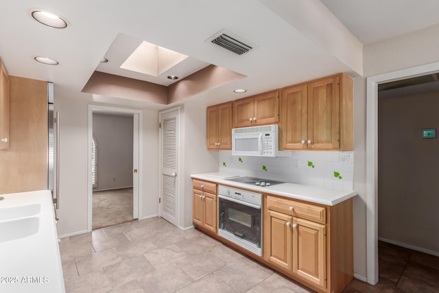 kitchen featuring white appliances, a skylight, baseboards, light countertops, and recessed lighting