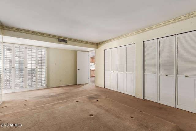 unfurnished bedroom with multiple closets and carpet