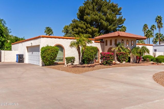 mediterranean / spanish-style home featuring concrete driveway, a garage, stucco siding, and a tiled roof