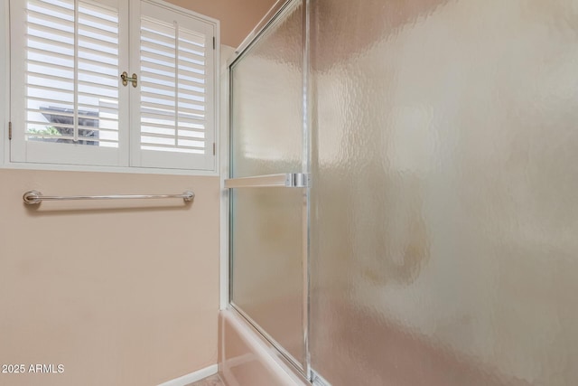 full bath featuring shower / bath combination with glass door and baseboards