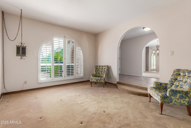living area featuring plenty of natural light, carpet floors, and arched walkways