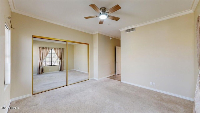 unfurnished bedroom with light carpet, crown molding, a closet, and ceiling fan