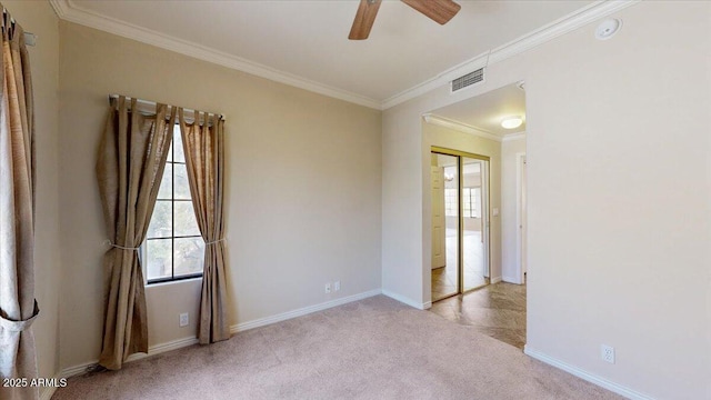 empty room featuring light carpet, plenty of natural light, ornamental molding, and ceiling fan