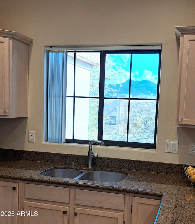 kitchen featuring a healthy amount of sunlight, sink, and dark stone counters