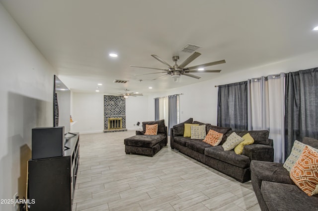 living area featuring a fireplace, visible vents, a ceiling fan, and recessed lighting