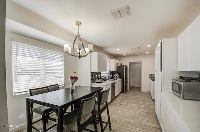 kitchen featuring light countertops, visible vents, appliances with stainless steel finishes, a sink, and light wood-type flooring