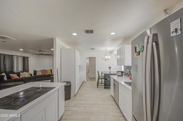 kitchen with appliances with stainless steel finishes, light countertops, visible vents, and white cabinetry