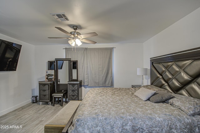 bedroom featuring a ceiling fan, wood finished floors, visible vents, and baseboards