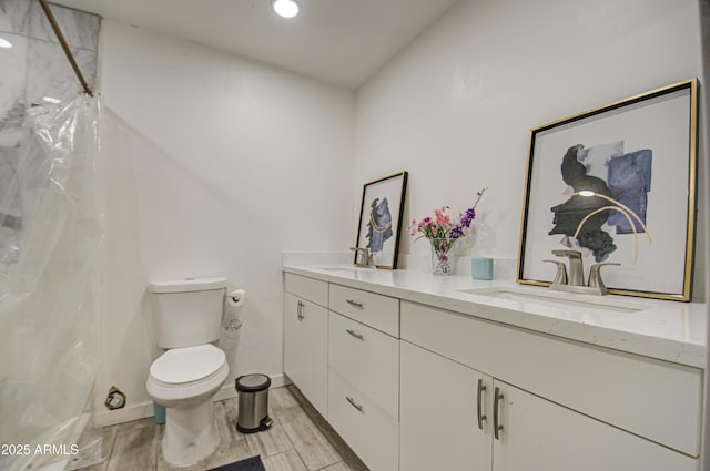 bathroom with double vanity, a shower with shower curtain, a sink, and toilet