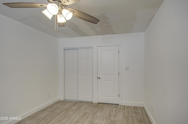 unfurnished bedroom with light wood-style floors, a closet, baseboards, and a ceiling fan