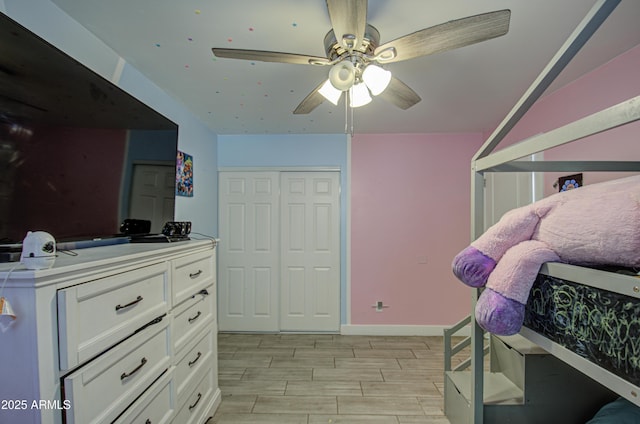 bedroom featuring wood tiled floor, baseboards, ceiling fan, and a closet