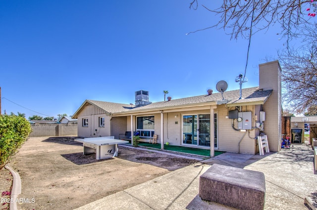 rear view of property with central AC unit, a patio, a chimney, fence, and board and batten siding