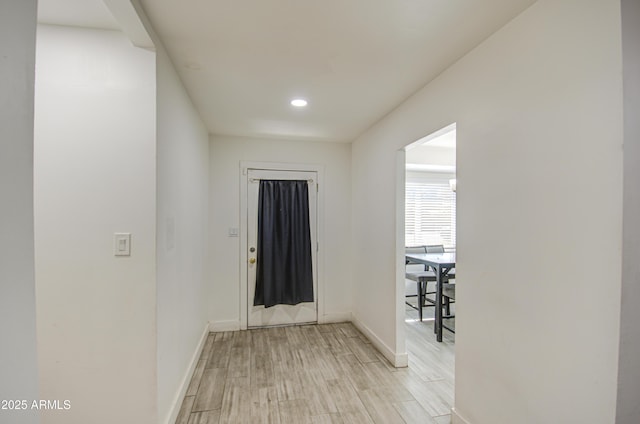 corridor with light wood-type flooring and baseboards