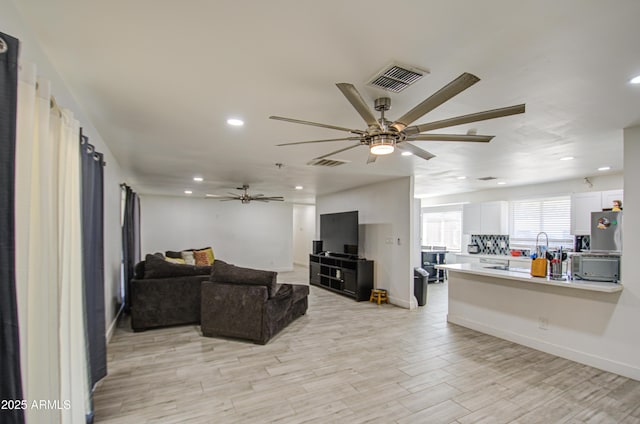 living room featuring a ceiling fan, light wood-type flooring, visible vents, and recessed lighting