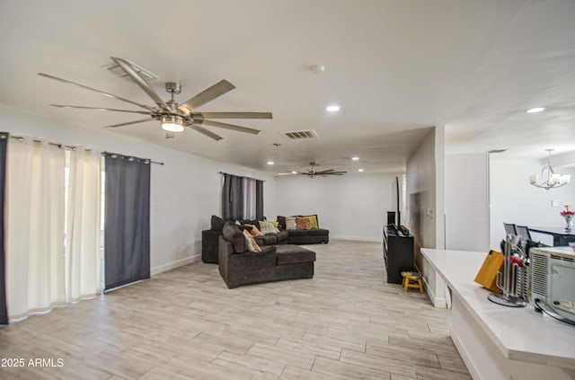 living area featuring light wood finished floors, visible vents, baseboards, ceiling fan with notable chandelier, and recessed lighting