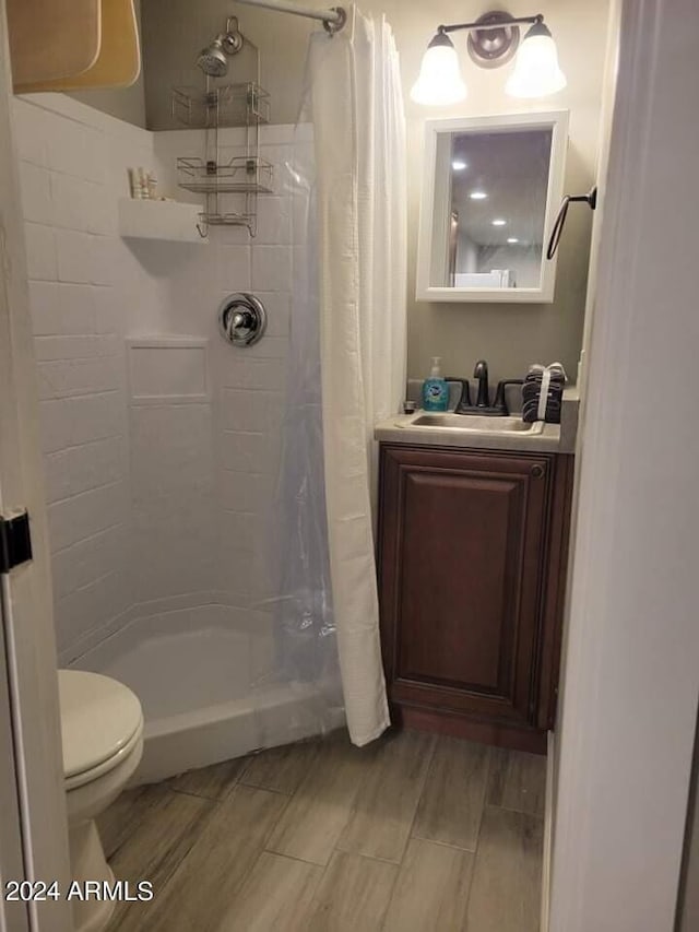 bathroom featuring a shower with curtain, hardwood / wood-style floors, vanity, and toilet