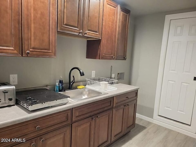 kitchen featuring light hardwood / wood-style floors, white stovetop, and sink