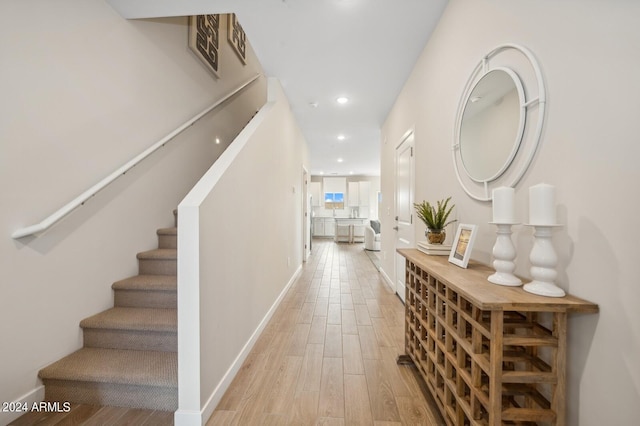 hallway with stairs, baseboards, light wood-style flooring, and recessed lighting