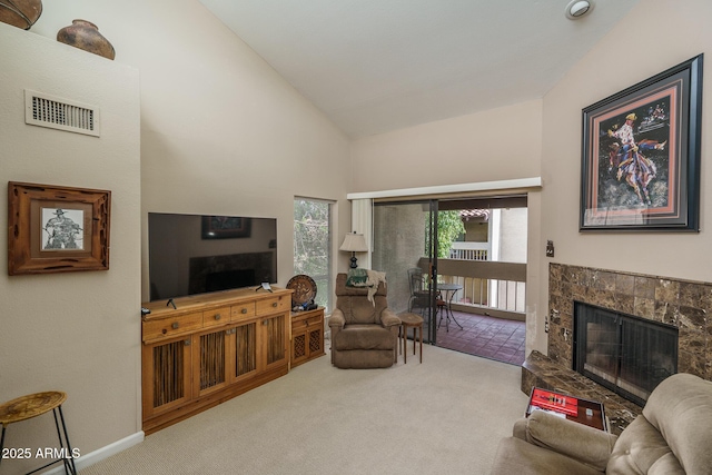 carpeted living area with high vaulted ceiling, baseboards, visible vents, and a tile fireplace