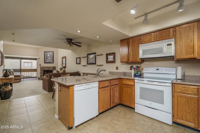 kitchen with a peninsula, white appliances, a fireplace, a sink, and open floor plan