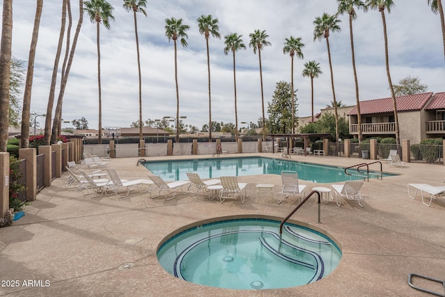 community pool featuring a patio, a hot tub, and fence