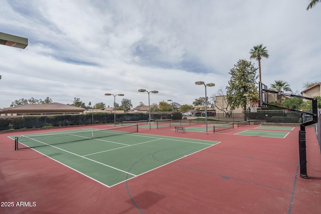 view of tennis court with community basketball court and fence