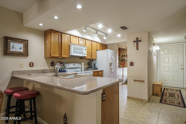 kitchen with white appliances, baseboards, visible vents, a breakfast bar, and a peninsula