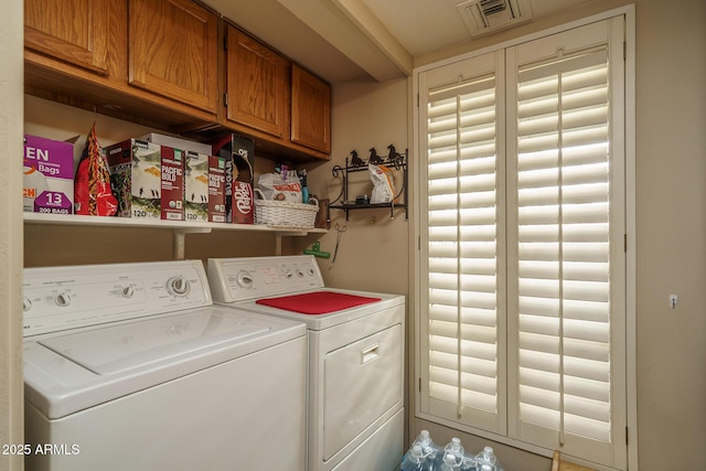 washroom with visible vents, cabinet space, and washer and clothes dryer