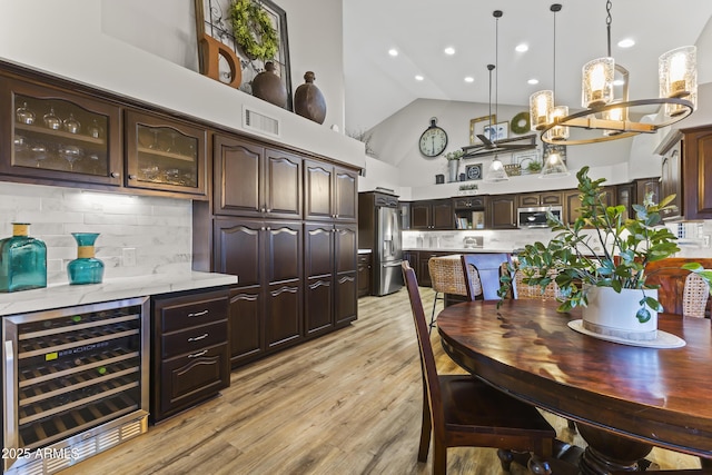 kitchen with appliances with stainless steel finishes, hanging light fixtures, tasteful backsplash, wine cooler, and dark brown cabinetry