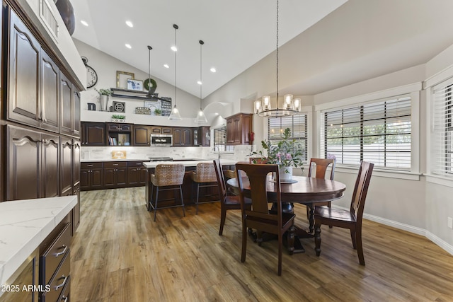 dining room with an inviting chandelier, high vaulted ceiling, and hardwood / wood-style floors