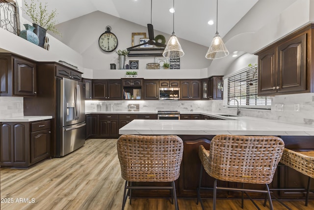 kitchen with appliances with stainless steel finishes, sink, a kitchen bar, kitchen peninsula, and dark brown cabinets