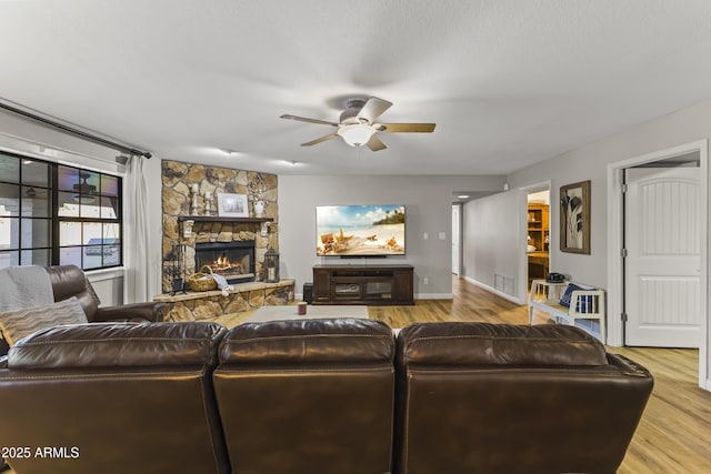 living room featuring a fireplace, light hardwood / wood-style floors, and ceiling fan