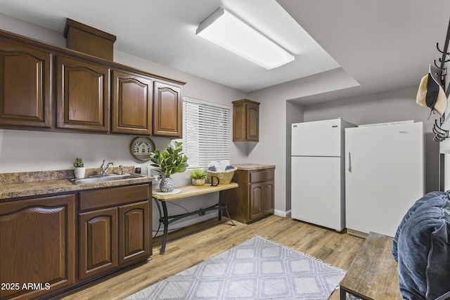 kitchen featuring sink, dark brown cabinets, light hardwood / wood-style flooring, and white refrigerator