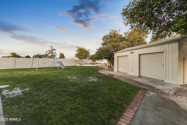 yard at dusk featuring a playground, a garage, and an outbuilding