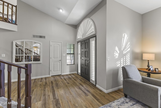 entryway with high vaulted ceiling and dark hardwood / wood-style floors