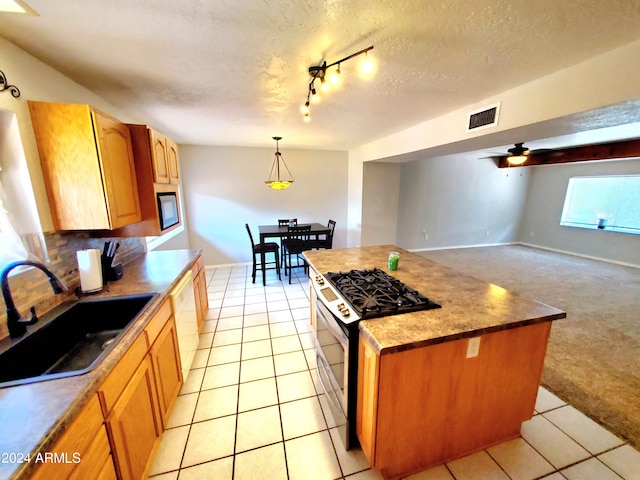 kitchen with light tile patterned floors, a center island, range with gas cooktop, pendant lighting, and sink