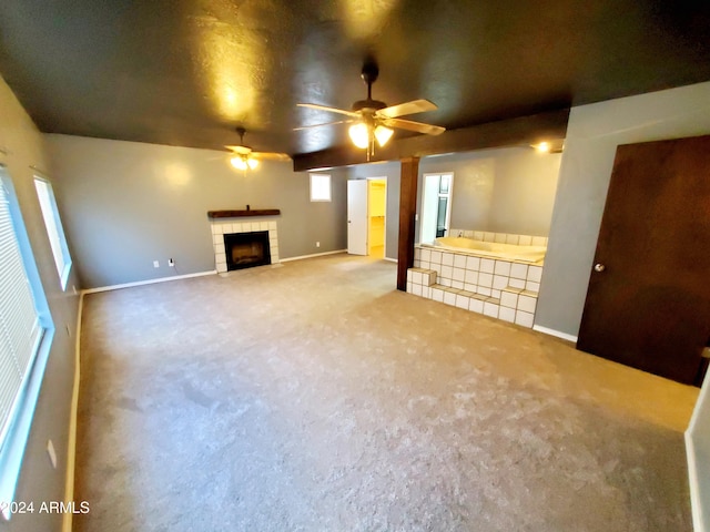 unfurnished living room featuring carpet, a tile fireplace, and ceiling fan