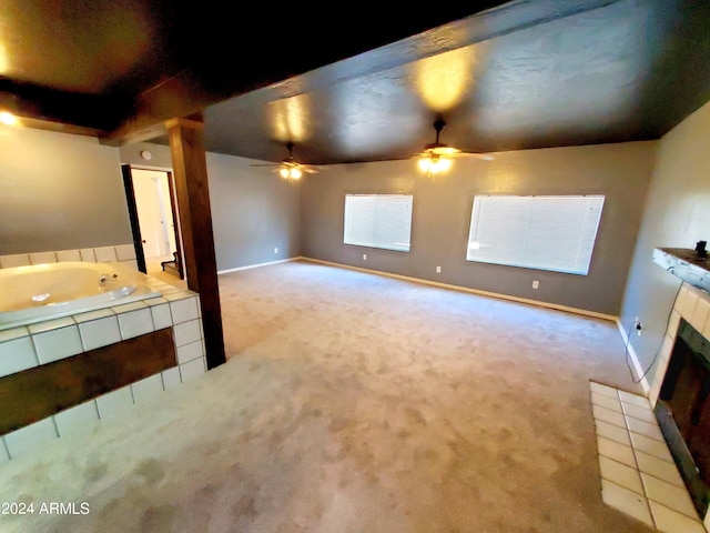 interior space featuring carpet floors, ceiling fan, and a tile fireplace