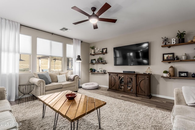 living room with visible vents, ceiling fan, baseboards, and wood finished floors