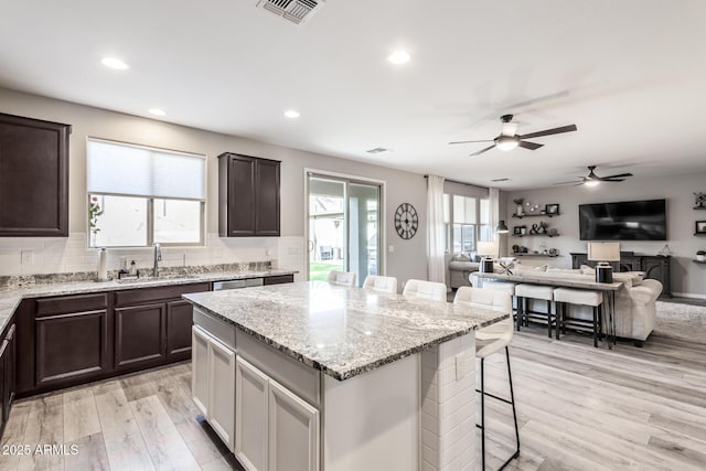 kitchen with dark brown cabinets, a kitchen bar, a sink, and visible vents