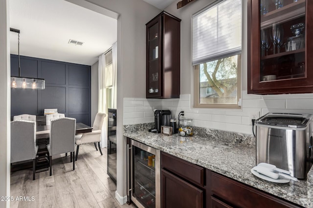 bar with pendant lighting, tasteful backsplash, visible vents, light wood-style flooring, and beverage cooler