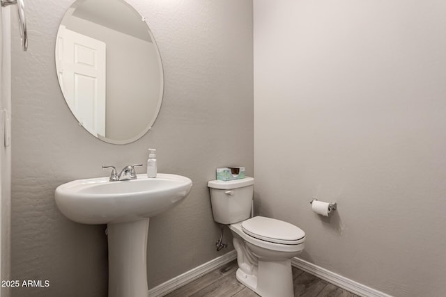 half bathroom with a sink, wood finished floors, toilet, and baseboards