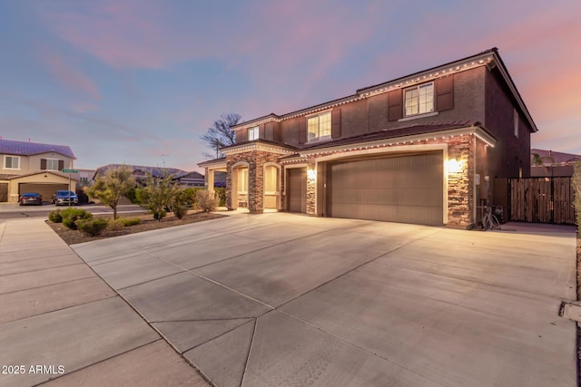 view of front of property featuring stone siding, concrete driveway, and stucco siding