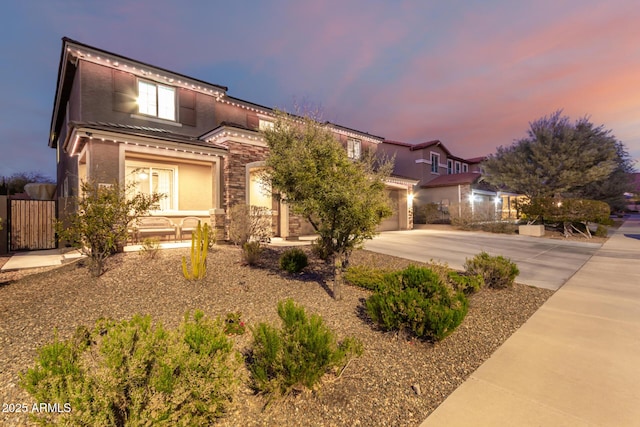 view of front of home with covered porch, concrete driveway, stone siding, and stucco siding