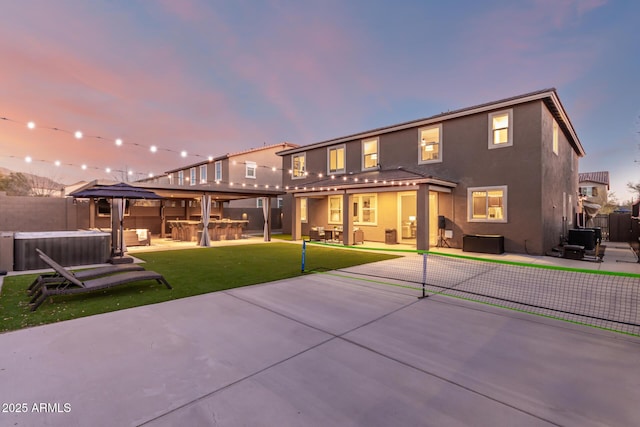 rear view of property with a patio, stucco siding, a hot tub, an outdoor kitchen, and a fenced backyard